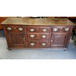 A 18th century oak dresser base, with fitted two cupboard section, three central short drawers and