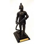 Bronzed-effect figure of a fireman with hose, on rectangular wooden base,