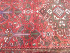 Eastern-style wool carpet, the red ground with central stepped medallion,