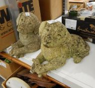 Two reconstituted stone dogs lying holding a bone, with glass eyes, 23cm approx.