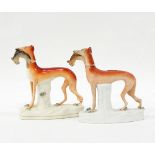 Two Staffordshire models of greyhounds, both with rabbits in their mouths, on naturalistic bases,