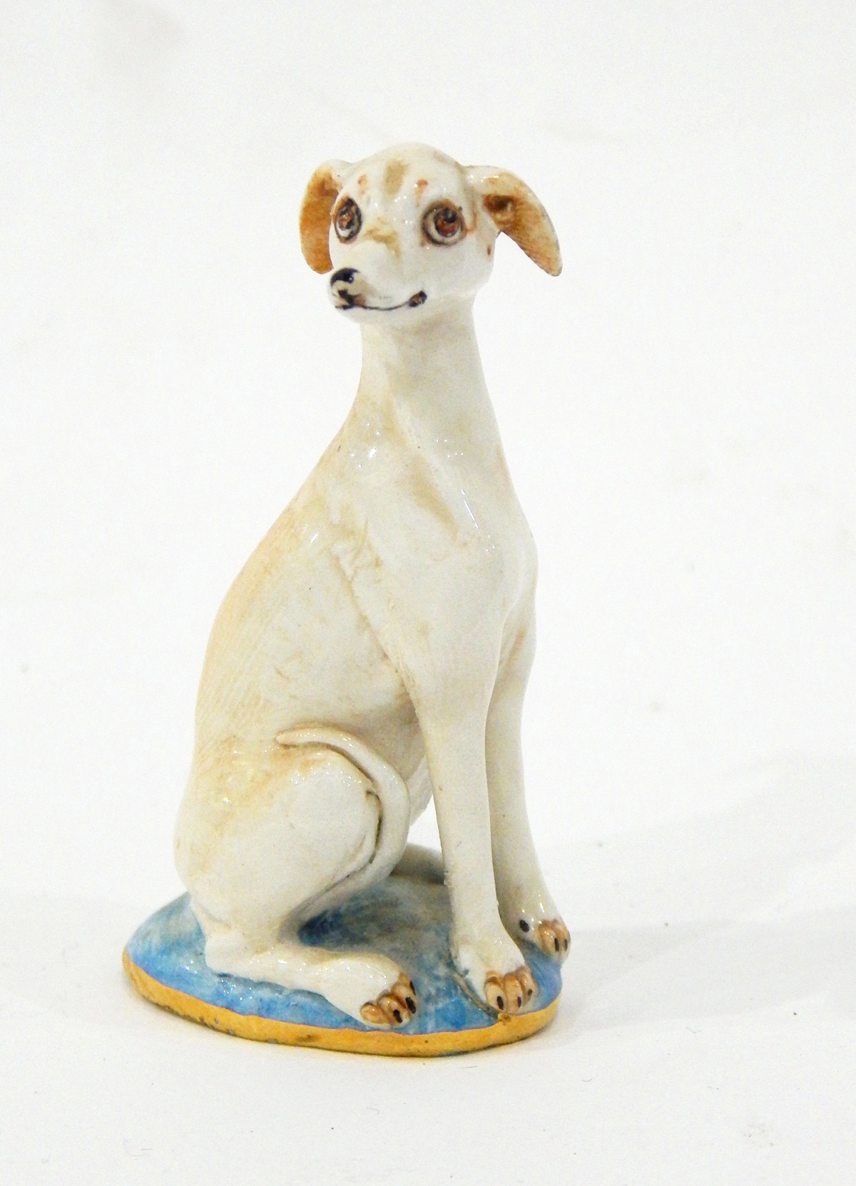 Porcelain model of a seated whippet, on oval base with gilt rim, the base signed "Basil Matthews",