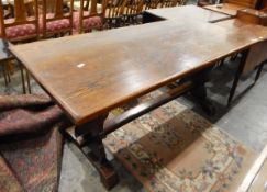 Oak refectory-style dining table on shaped end standards united by a straight stretcher,