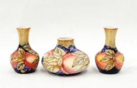 Pair of vases with tube lined decoration, of berries and fruit in the Moorcroft style,