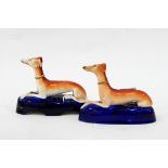 Pair of Staffordshire models of recumbent greyhounds and a pair of Staffordshire pen stands