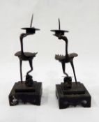 Pair of Chinese metal pricket candlesticks modelled as storks, bearing drip pans, on square bases,