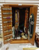 Wooden jewellery cabinet and contents of costume jewellery including amber beads, haematite beads,