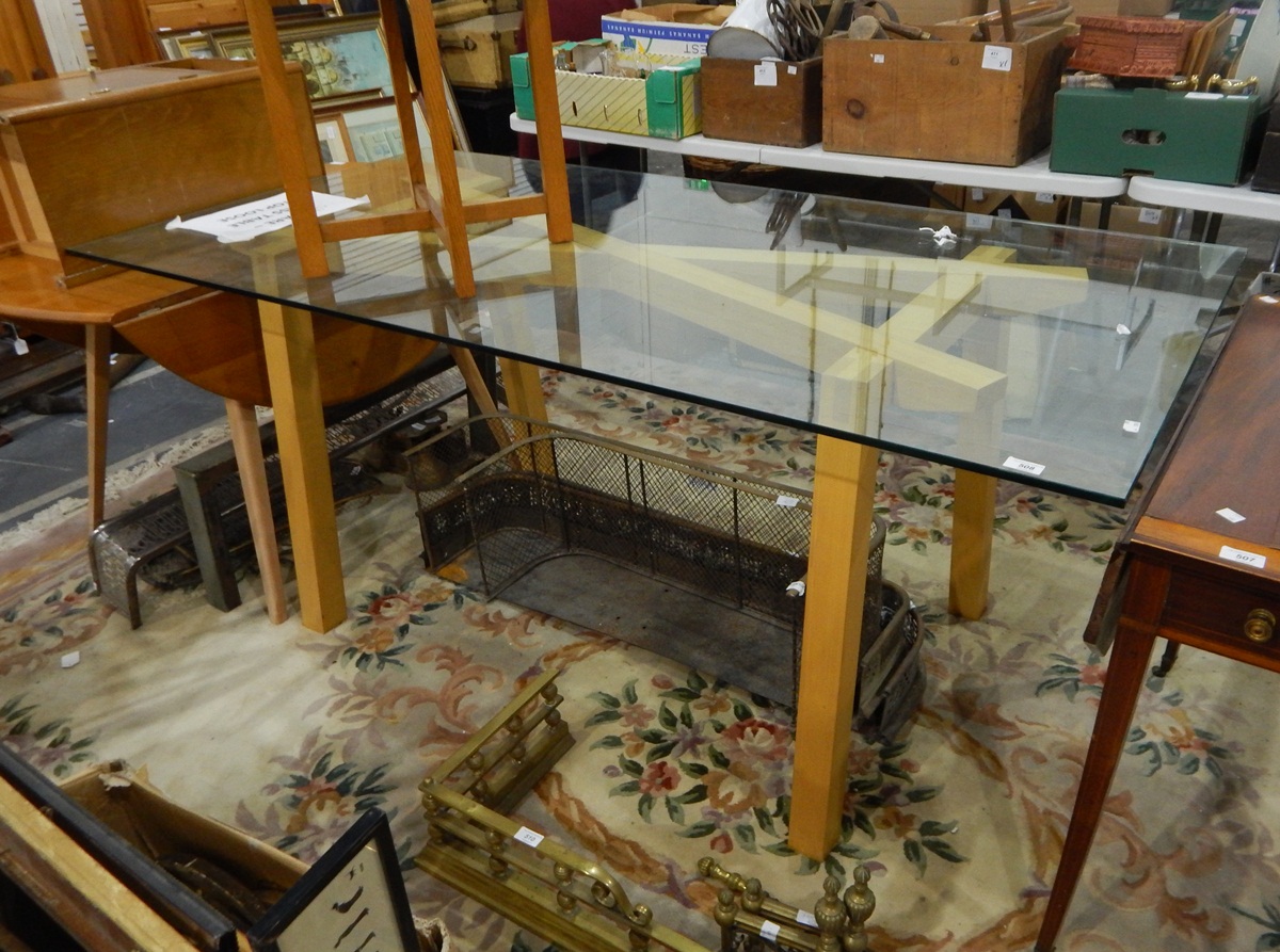 Modern glass-topped dining table on unstained beech supports