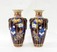 Pair of Japanese baluster vases, each decorated with flowers on a brown ground,