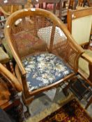 Cane backed tub armchair on cabriole supports and claw and ball feet and a stool (2)