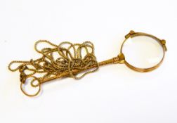 A gold rolled metal folding lorgnette with scroll engraved stem on snake link necklace
