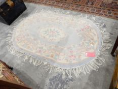 A Chinese wool washed rug, oval shape, pink on a blue ground,