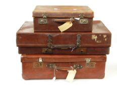 Three leather suitcases, one with various shipping labels,