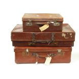 Three leather suitcases, one with various shipping labels,