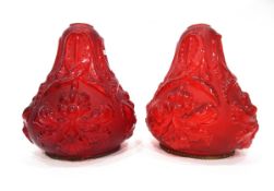 Pair of red glass light shades, each of bulbous form moulded with flowerheads and leaves,