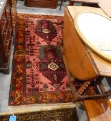 Handmade Eastern wool rug with pink ground, two geometric stylised vases of flowers,