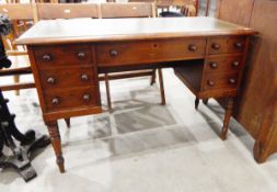 Oak writing desk the top with tooled leather insert over an arrangement of seven drawers,