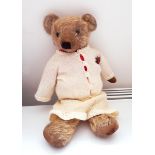 Vintage Merrythought mohair bear with glass eyes wearing a knitted skirt and cardigan,