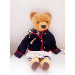 Large gold plush bear wearing a sailor suit and a jacket with bell and medal,