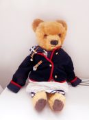 Large gold plush bear wearing a sailor suit and a jacket with bell and medal,