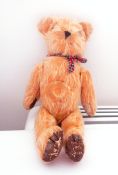 Early bear with tartan ribbon around his neck,