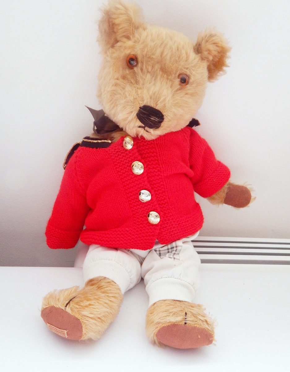 Chad Valley plush bear wearing dungarees with a red knitted cardigan and with military buttons,