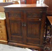 Oak side cabinet with carved linenfold panel doors enclosing shelf, raised on bracket feet,