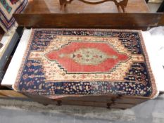 Small handmade Persian rug with blue ground, central pink and beige geometric motif,