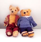Two plush teddy bears with glass eyes, one wearing a smart maroon and patterned suit,