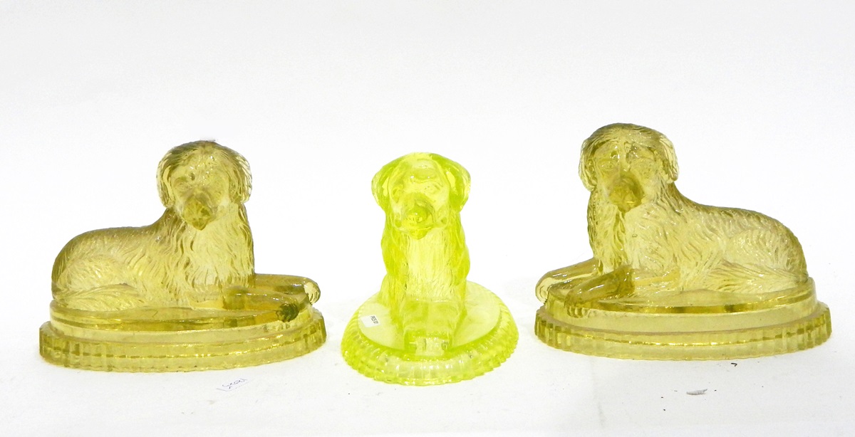 Pair of Victorian yellow pressed glass models of recumbent dogs on oval bases,