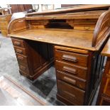 Oak roll-top desk with fitted interior, four short drawers to either side, on a plinth base,