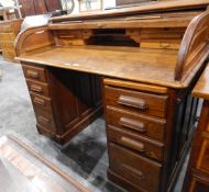 Oak roll-top desk with fitted interior, four short drawers to either side, on a plinth base,