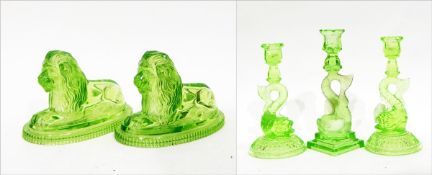 Pair of John Derbyshire green pressed glass lion ornaments, the recumbent lions on oval bases,