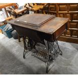 An old treadle sewing machine on original table with cast iron supports and treadle platform,