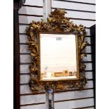 Pair of rococo style wall mirrors with carved foliate gilt frames, and rectangular bevelled plates,