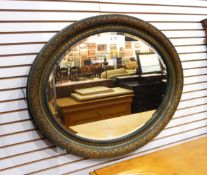 An oval wall mirror in a moulded gilt frame with oval plate,
