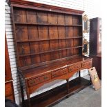 George III oak dresser with three shelf plate rack above four frieze drawers, with a shaped apron,