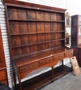 George III oak dresser with three shelf plate rack above four frieze drawers, with a shaped apron,