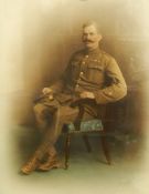 Early 20th century coloured portrait photograph of a seated soldier in army uniform,