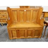 Small pine settle with full panelled back, the hinged box seat enclosing compartment,
