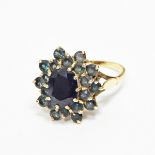 Gold cluster ring, the central oval sapphire surrounded by two rows of circular cut green stones,
