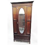 Early 20th century mahogany wardrobe with oval bevel plate mirror door enclosing hanging space with