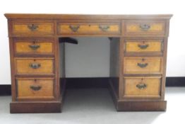 Edwardian oak kneehole pedestal desk having an arrangement of nine drawers with brass bale handles