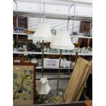 Two brass standard lights on square bases with shades, a similar table lamp,