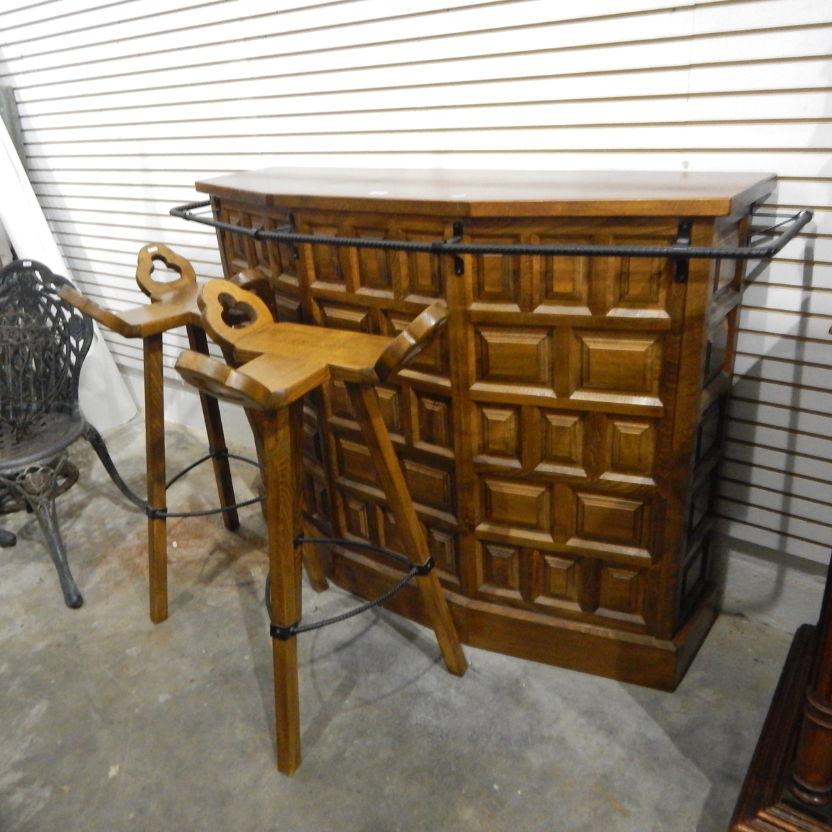 A modern panelled oak bowfront bar with metal rail, and a pair of bar stools,