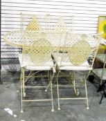 Cream painted metal table and four chairs, with open latticework design,