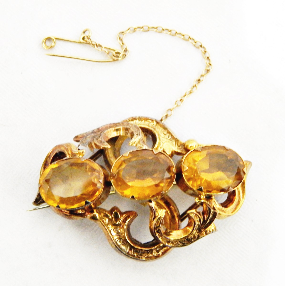 Victorian gold-coloured metal and citrine brooch set three oval cut stones within engraved scrolled