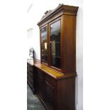 Edwardian walnut bookcase on cupboard having carved and shaped pediment over dentil cornice,