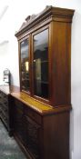 Edwardian walnut bookcase on cupboard having carved and shaped pediment over dentil cornice,