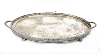 Silver-plated two-handled tray of oval form with pierced gallery on four bun feet,